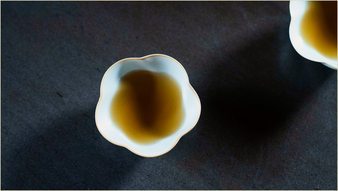 A top view of a flower shape tea bowl on a table with Red Oolong tea inside.